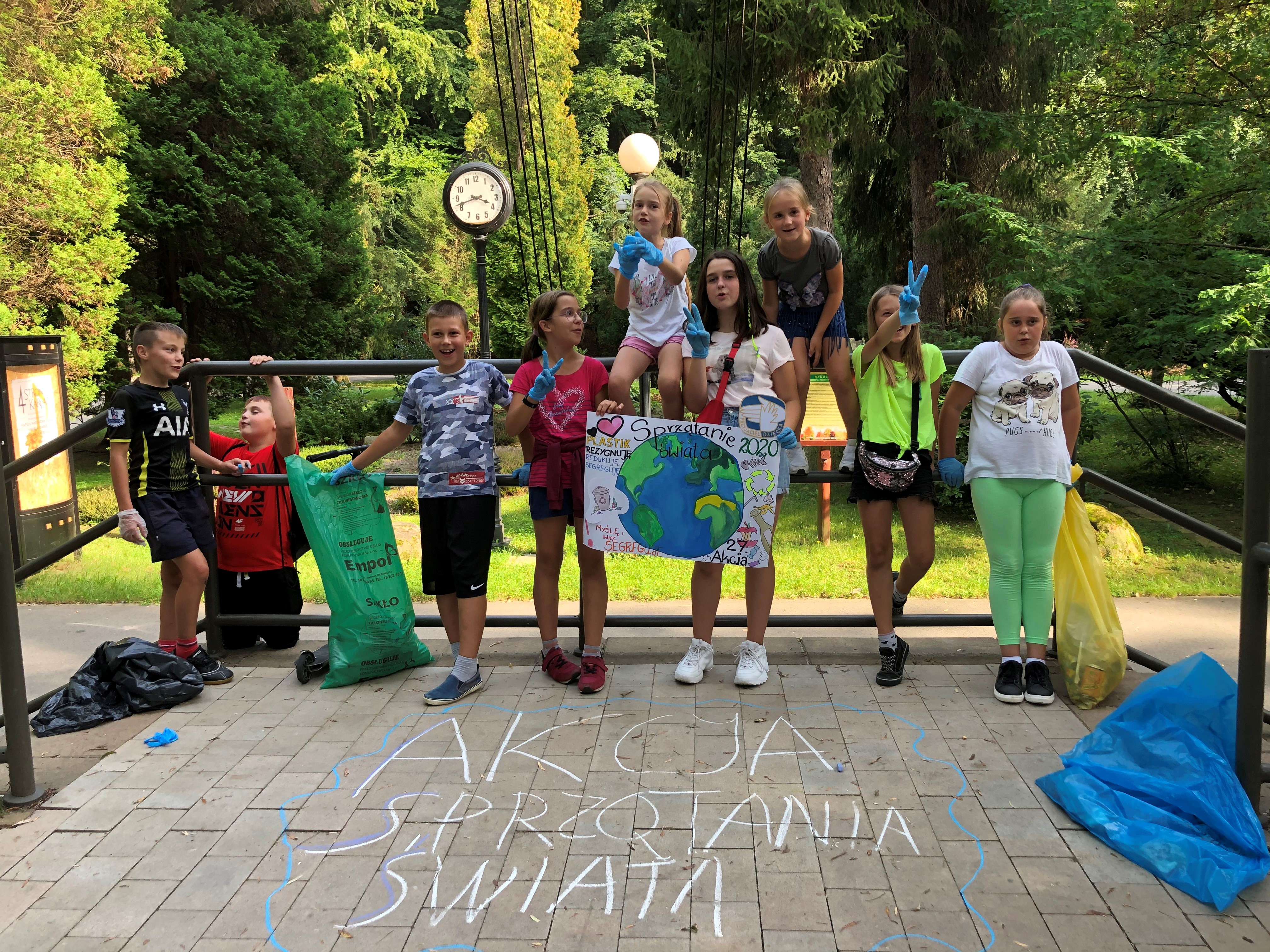 Grupka dzieci stojąca w Parku Miejskim w Gorlicach z plakatem promującym akcję sprzątania świata