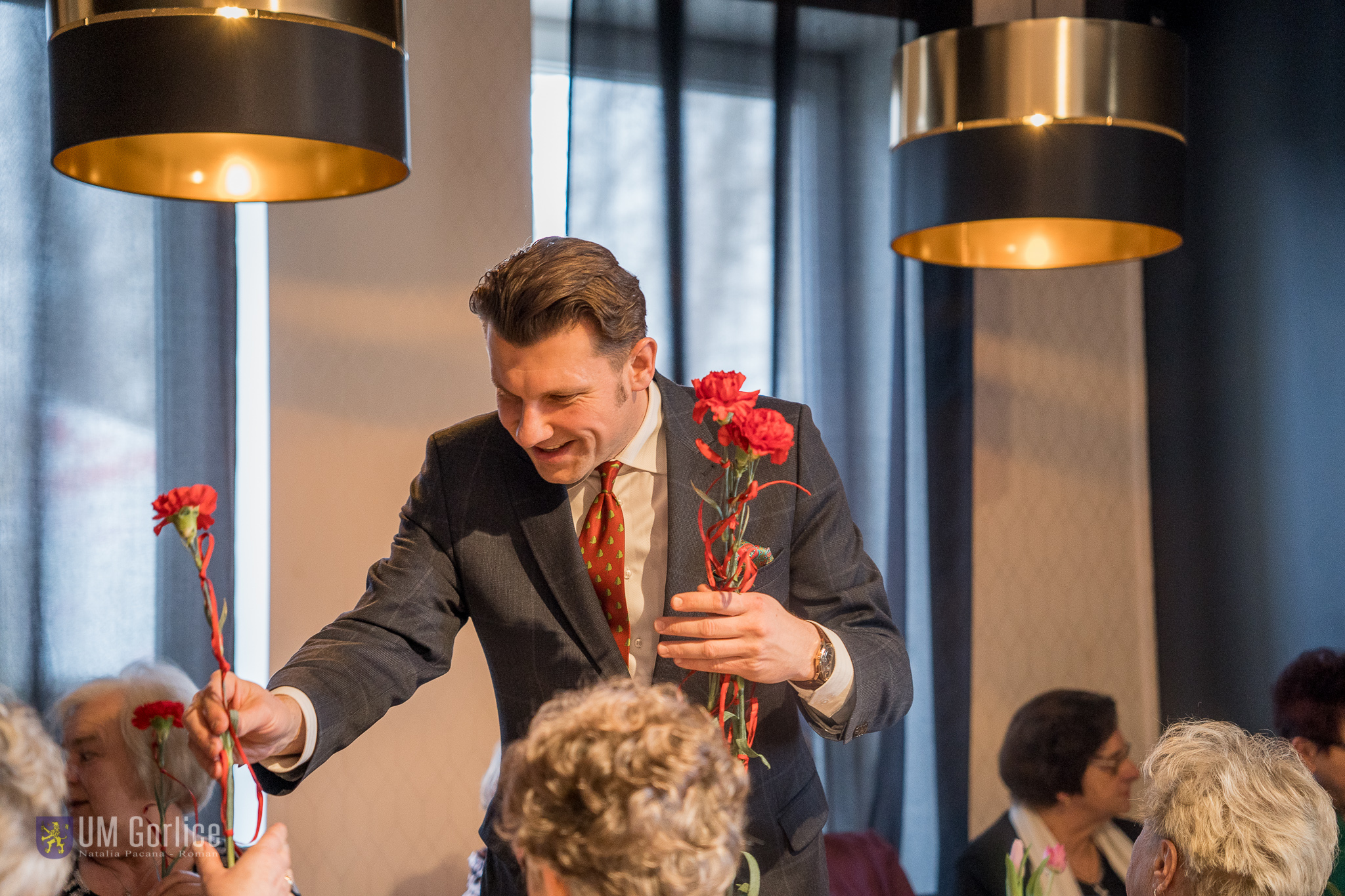Biurmistrz Rafał Kukla wręczający kwiaty z okazji Dnia Kobiet na spotkaniu zorganizowanym przez Osiedle Młodych