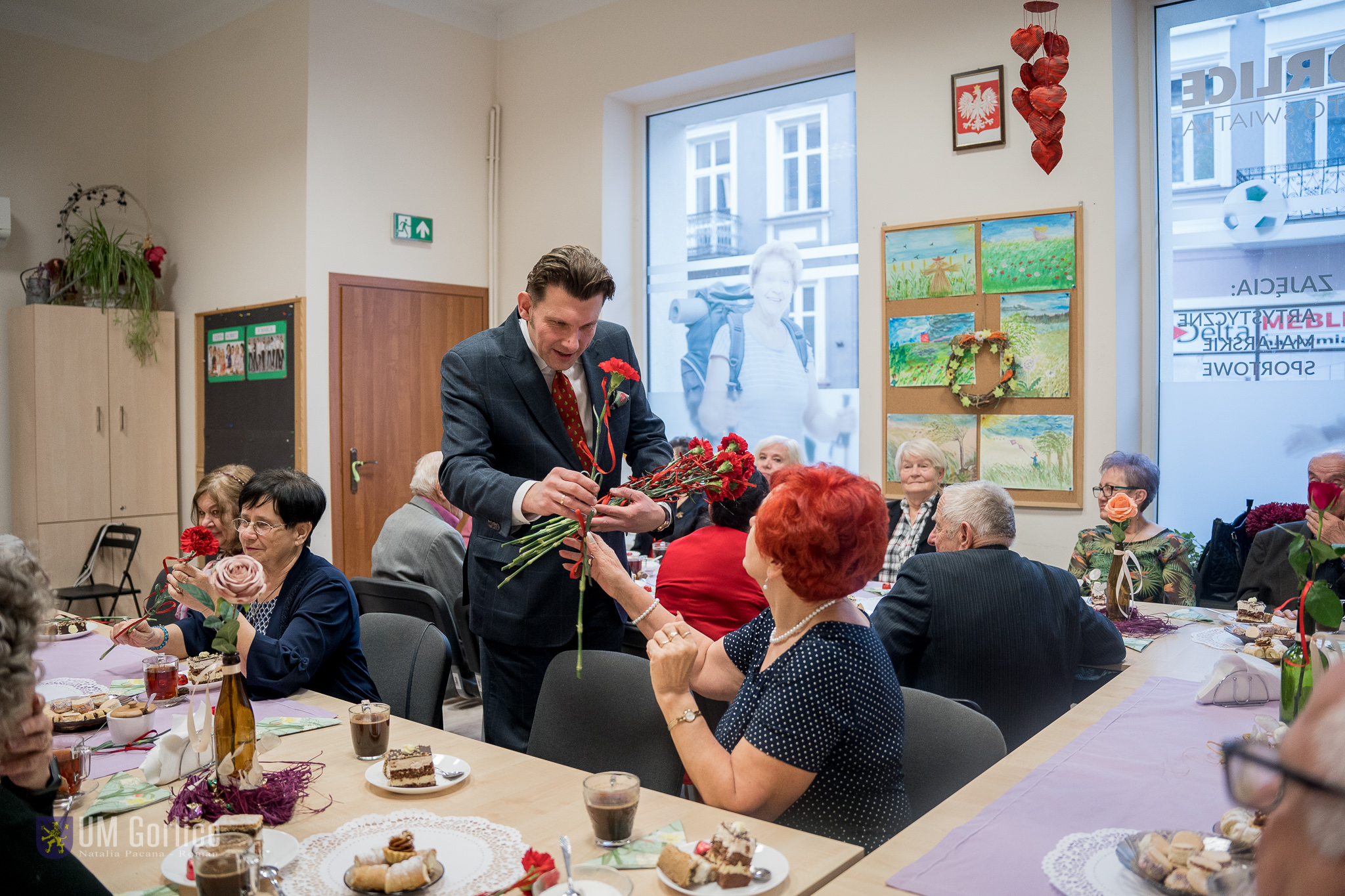 Burmistrz Rafał Kukla wręczający kwiaty paniom z Klubu Seniora, na spotkaniu z okazji Dnia Kobiet