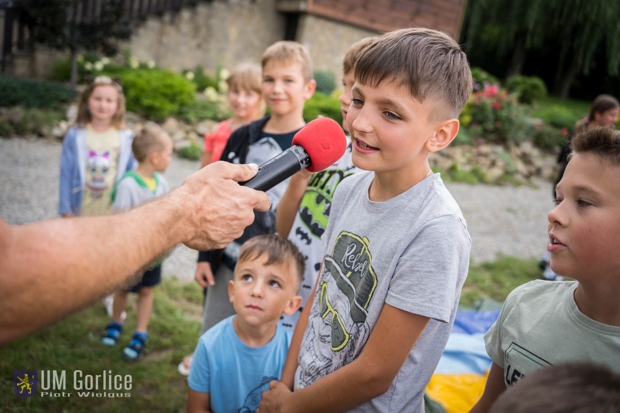 Chłopiec śpiewa na pierwszym planie do mikrofonu.