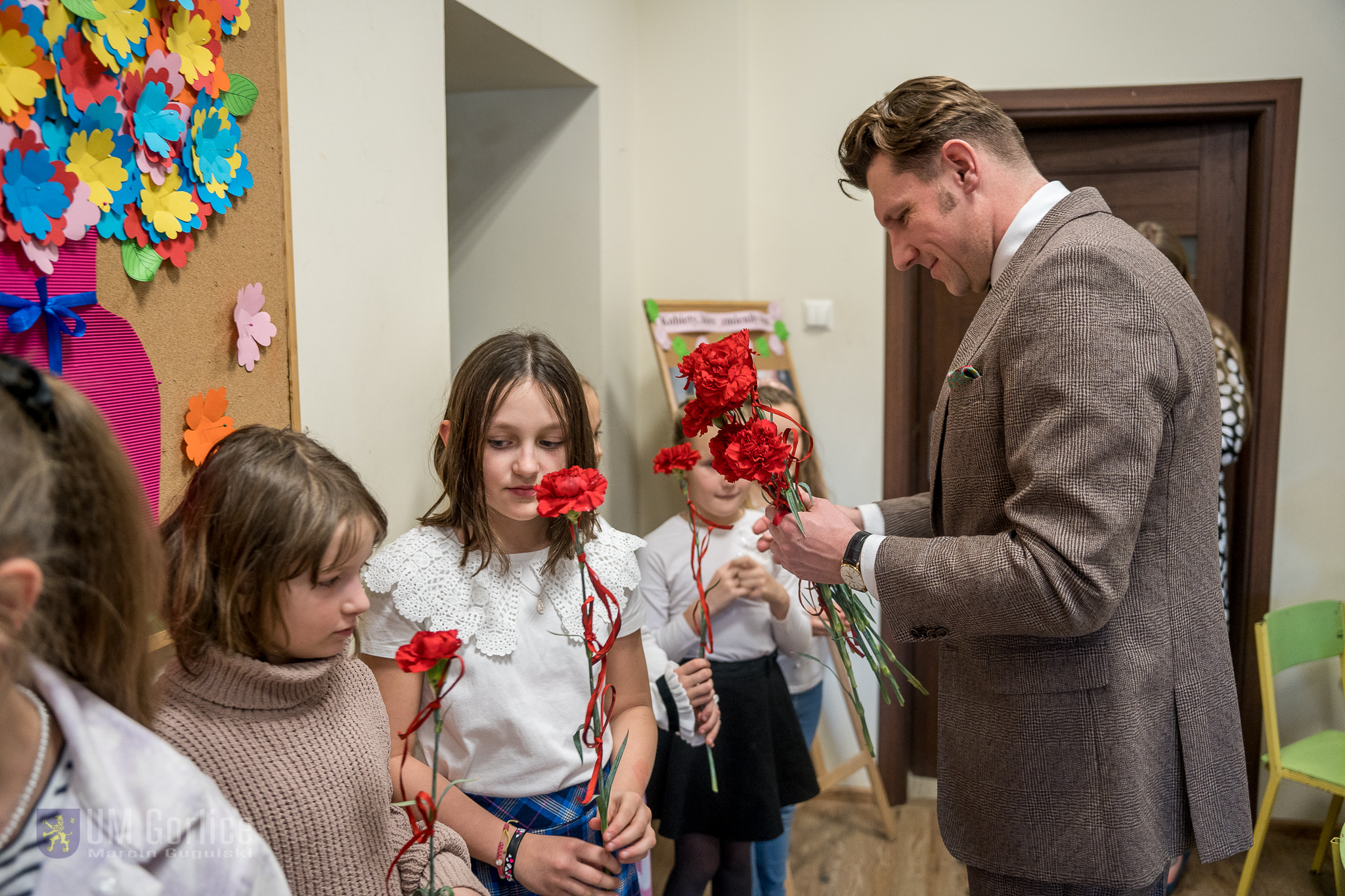 Burmistrz Rafał Kukla wręczający goździki z okazji Dnia Kobiet w Towarzystwie Przyjaciół Dzieci