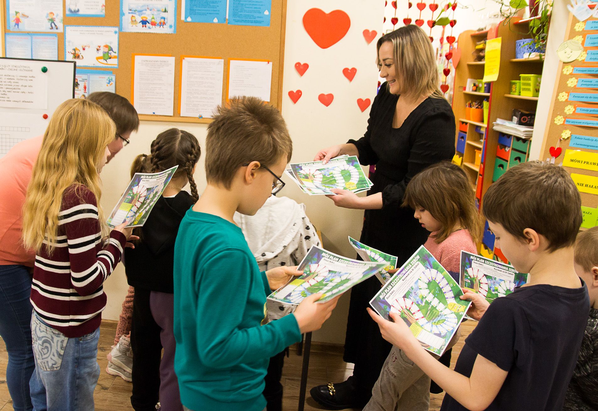 Dzieci trzymają w rękach malowanki otrzymane od pracownika Sanepidu.