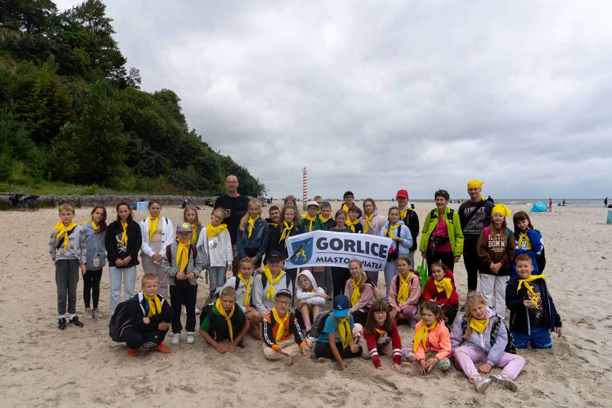 Dzieci pozują w grupie na plaży w flagą Gorlic.