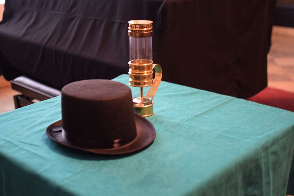 Lampa naftowa i kapelusz na stole.