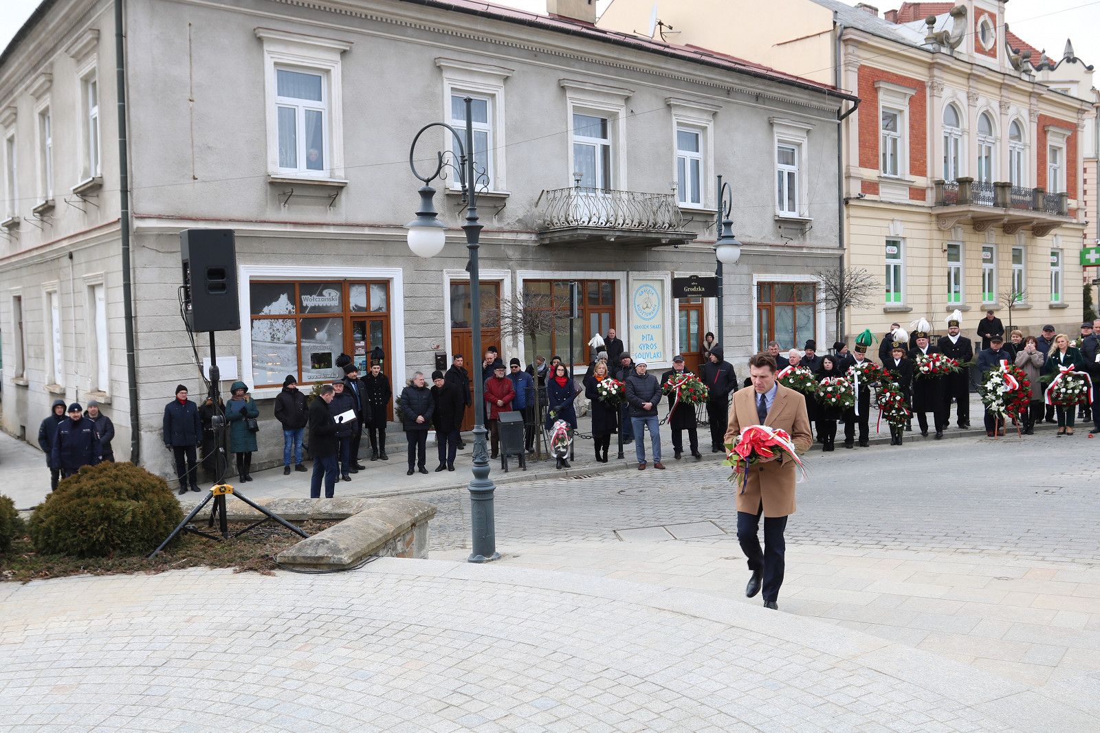 Rafał Kukla składa kwiaty przed pomnikiem Łukasiewcza.