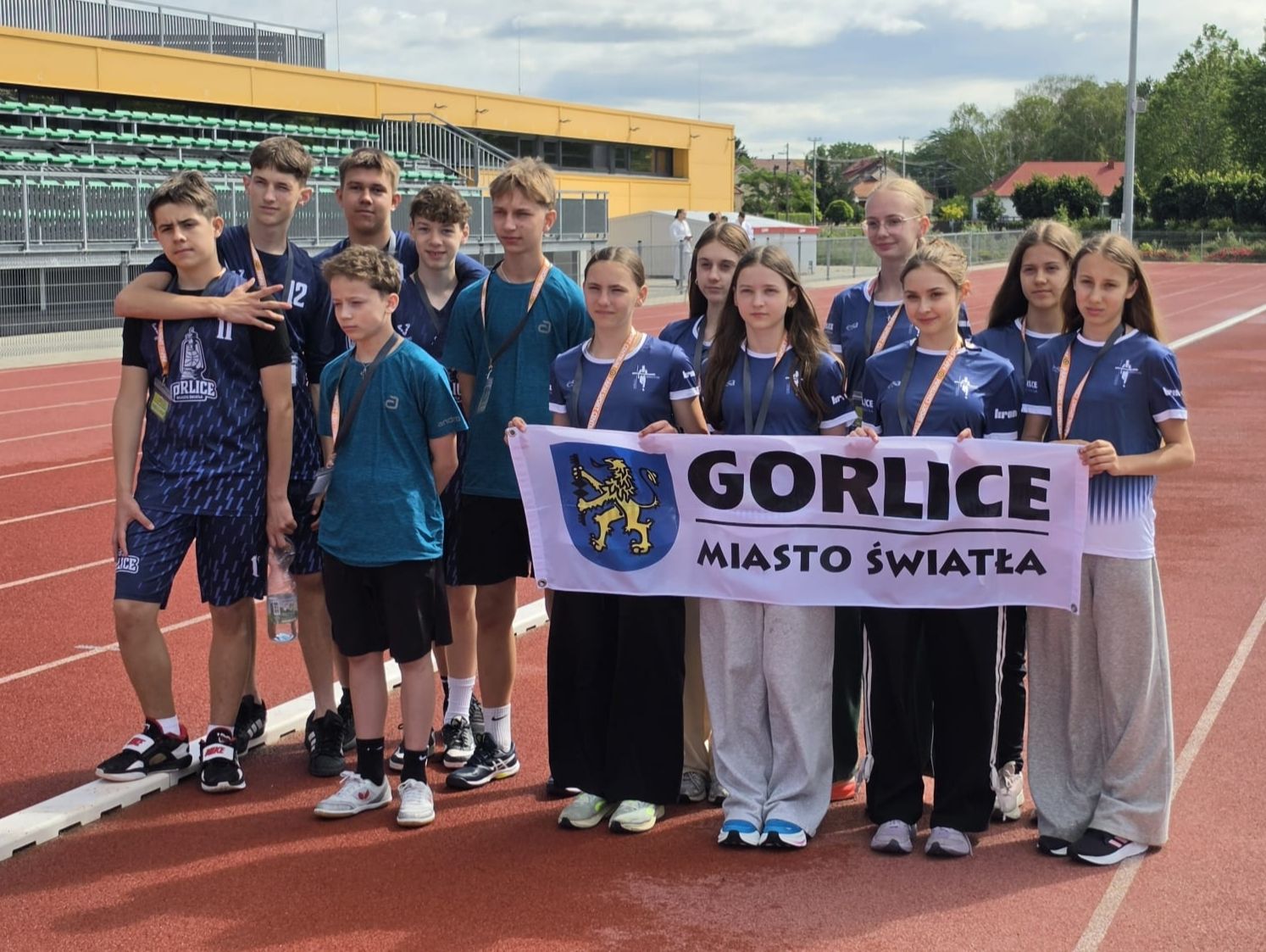 Zdj grupowe zawodników na stadionie.