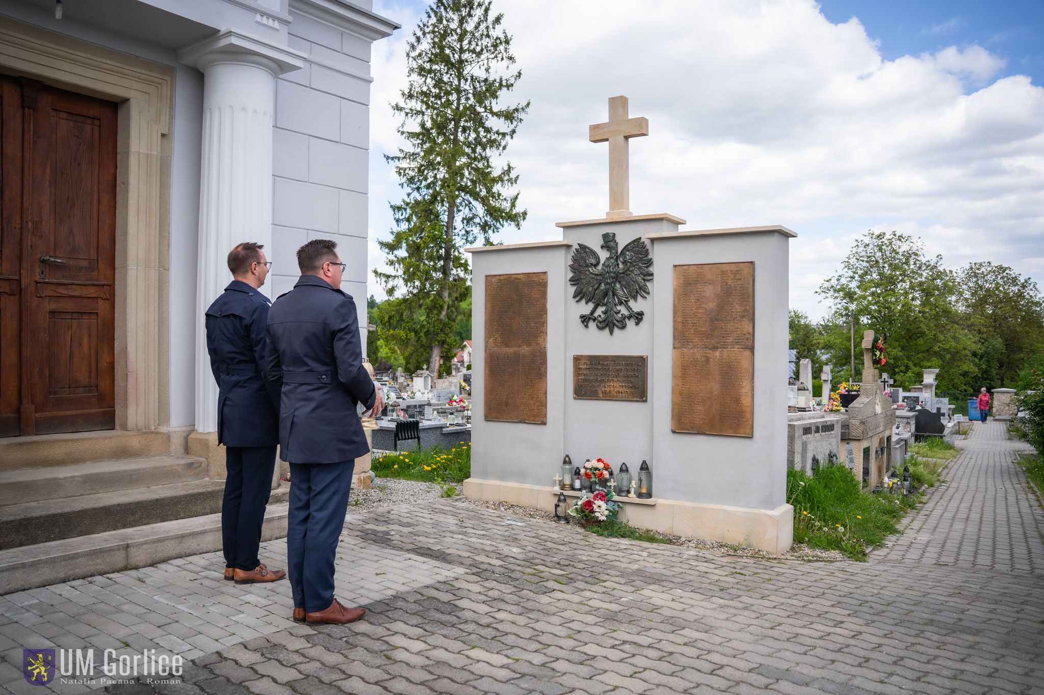 Zastępca burmistrz i sekretarz składają znicz na cmentarzu parafialnym.