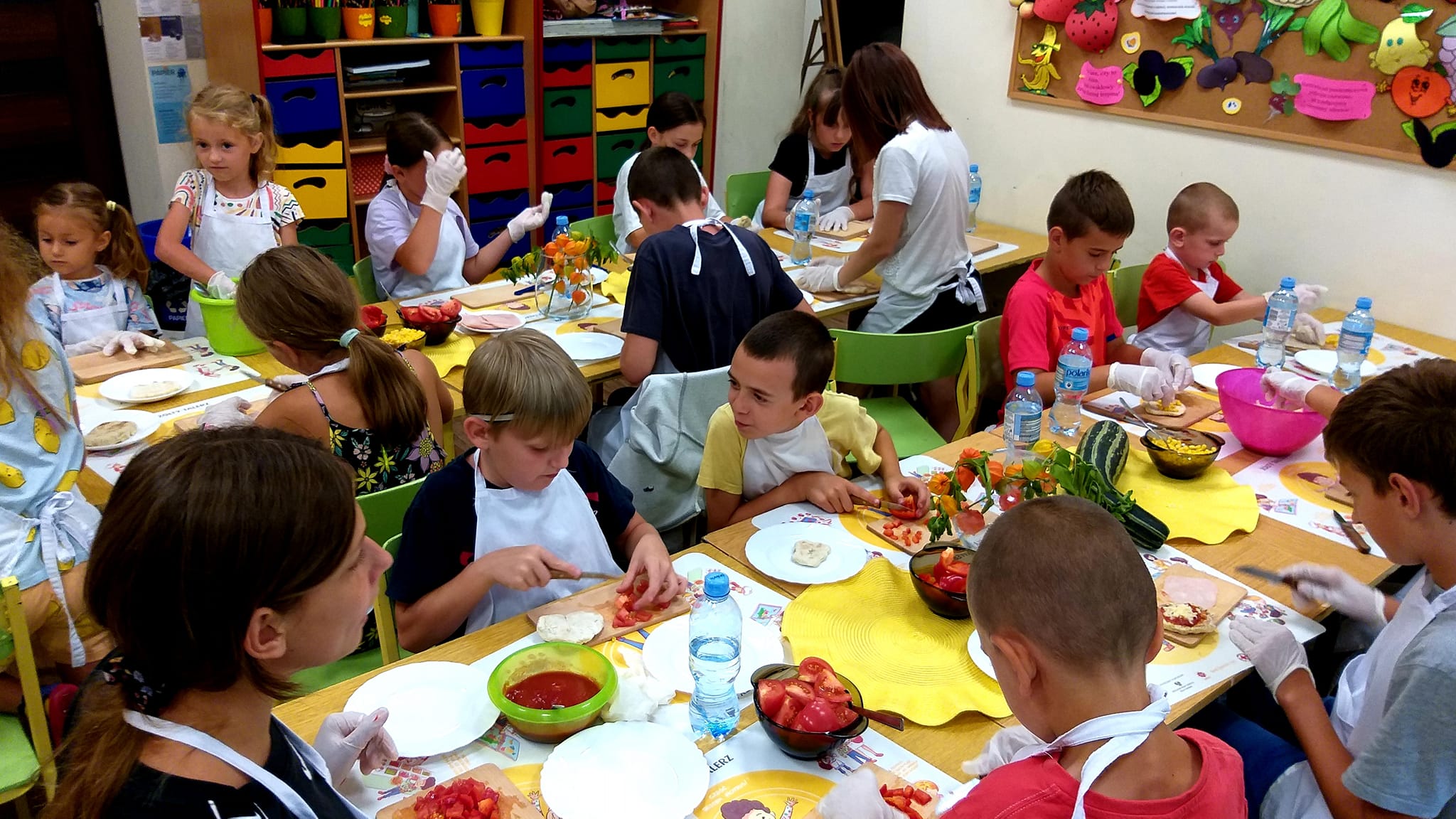 Dzieci w trakcie krojenia pomidorów na stole.