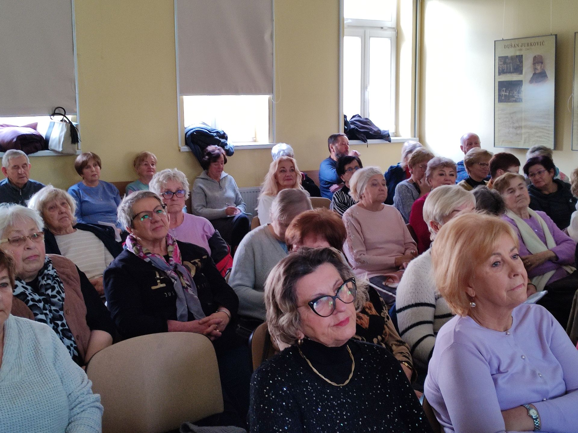 Seniorzy na sali, słuchają wykładu.