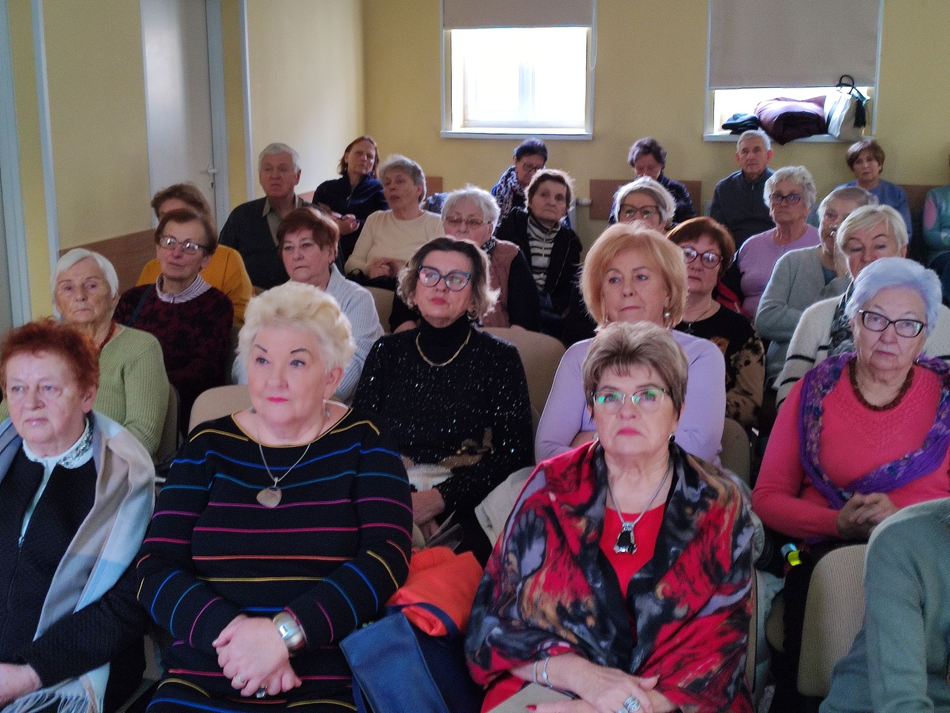 Seniorzy na sali, słuchają wykładu.