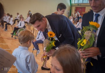 Burmistrz Rafał Kukla wręczający kwiaty pierwszoklasistom