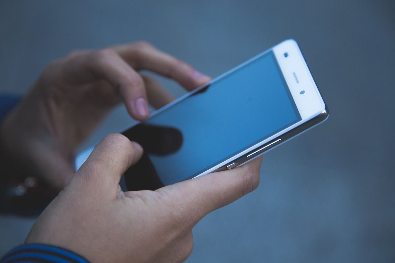 Telefon komórkowy trzymany w rękach.