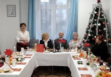 Goście podczas spokania wigilijnego siedzą przy stole.